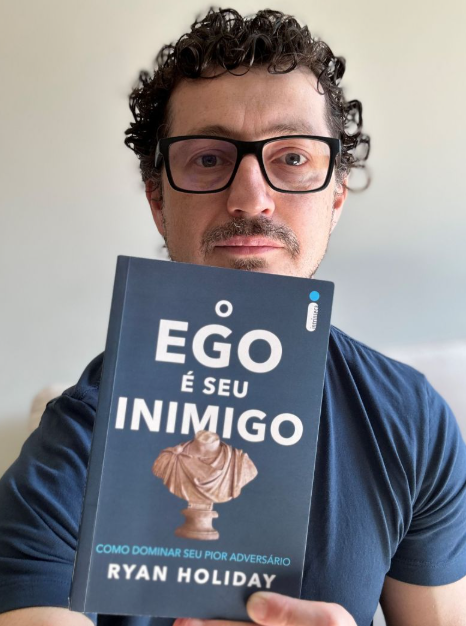 Cezar Cattani segurando o livro O Ego é Seu Inimigo, de Ryan Holiday