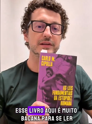 Cezar Cattani segurando o livro As Leis Fundamentais da Estupidez Humana, de Carlo M. Cipolla