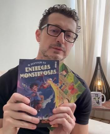Cezar Cattani segurando o livro infantil O Serviço de Entregas Monstruosas
